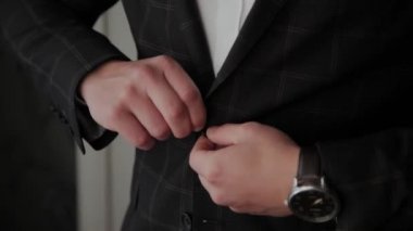 Stylish male businessman straightens his jacket.