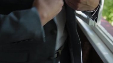 Stylish male businessman straightens his jacket.