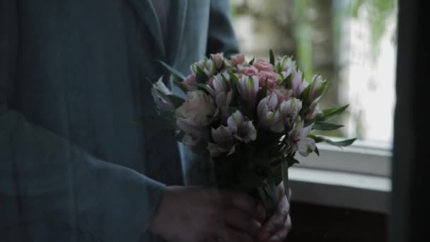 Un giovane uomo con un bouquet da sposa in mano . — Video Stock