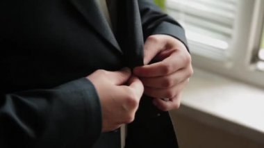 Stylish male businessman straightens his jacket.