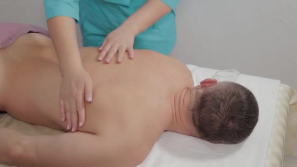 Female massage therapist doing a relaxing massage to a man in a massage parlor. — Stok video