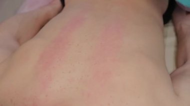 Female massage therapist doing a relaxing massage to a man in a massage parlor.
