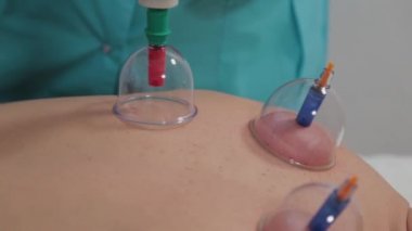 Doktor, bir adamın sırtına elektrikli süpürge koyuyor..