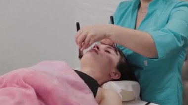 Kadın masaj terapisti müşteriye yüz masajı yapıyor..