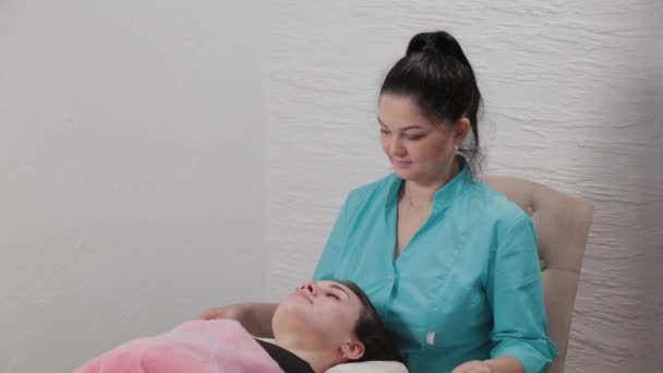 Vrouw massage therapeut doet gezicht borstel massage naar klant. — Stockvideo