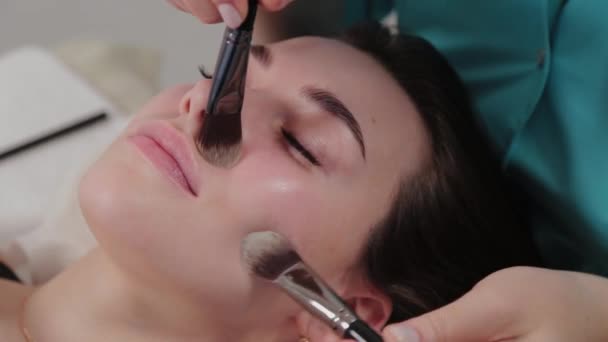 Vrouw massage therapeut doet gezicht borstel massage naar klant. — Stockvideo