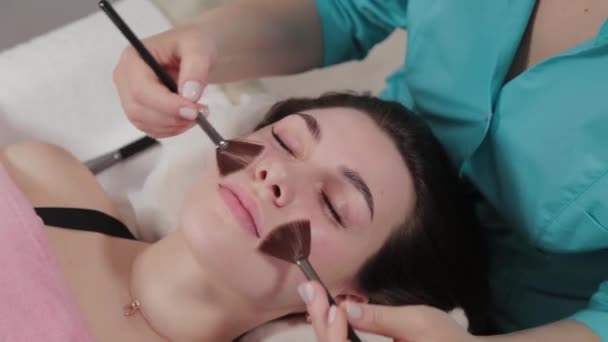Donna massaggiatrice fa massaggio viso pennello al cliente . — Video Stock