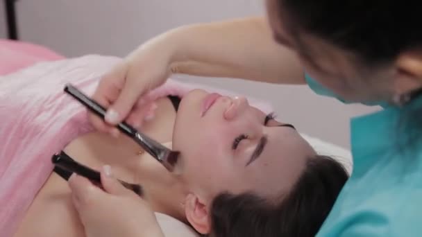 Mujer terapeuta de masaje hace masaje con cepillo facial al cliente . — Vídeos de Stock