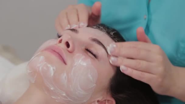 Жінка масажистка виконує масаж обличчя клієнту масажного салону . — стокове відео