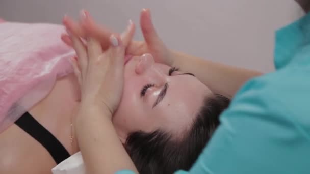 Mujer masajista terapeuta realiza masaje facial al cliente del salón de masajes . — Vídeos de Stock