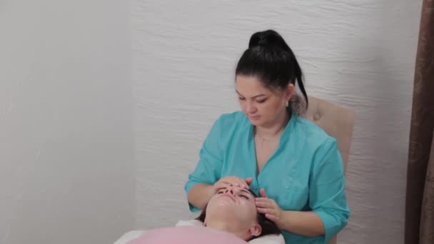 Mujer masajista terapeuta realiza masaje facial al cliente del salón de masajes . — Vídeos de Stock