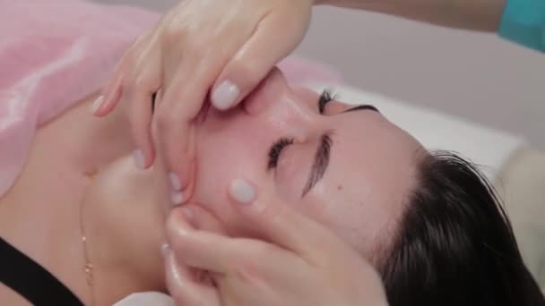 Mulher massagista terapeuta realiza massagem facial para o cliente do salão de massagem . — Vídeo de Stock