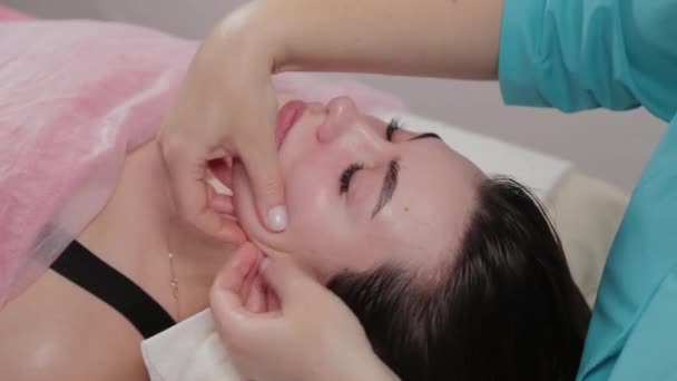 Mujer masajista terapeuta realiza masaje facial al cliente del salón de masajes . — Vídeos de Stock