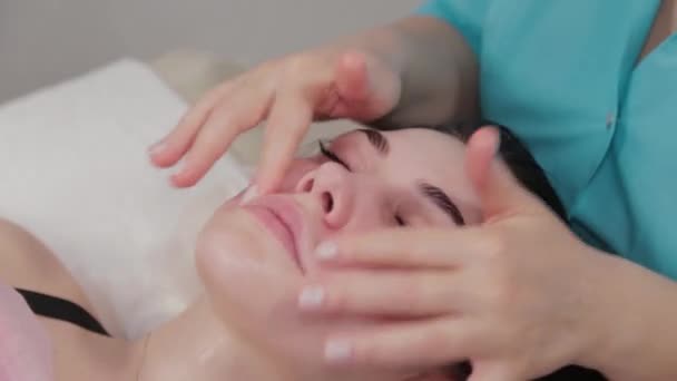 Woman massage therapist performs facial massage to the client of the massage parlor. — Stock Video