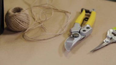 Çiçekçilerin çalışma aletleri çiçeklerle dolu bir masada yatıyor..