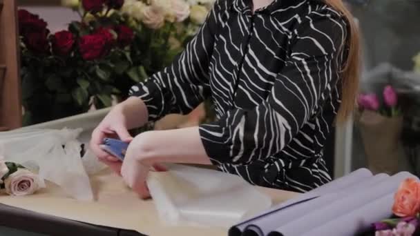 Επαγγελματίας ανθοπώλης ετοιμάζει συσκευασία για λουλούδια. Όμορφο μπουκέτο για τη Διεθνή Ημέρα της Γυναίκας. — Αρχείο Βίντεο