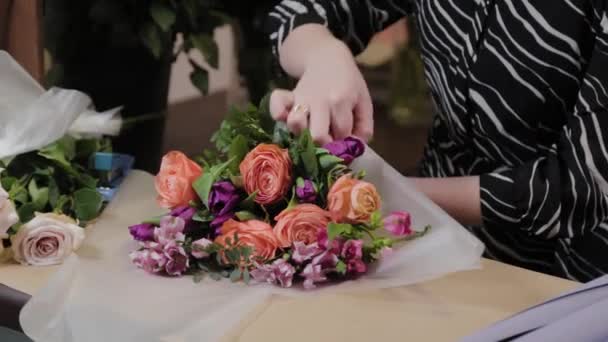 Professionele bloemist is het inpakken van een boeket. Mooi boeket voor Internationale Vrouwendag. — Stockvideo