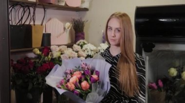 Profesyonel çiçekçi bir buketi ipek kurdeleyle bağlar. Uluslararası Kadınlar Günü için güzel bir buket.