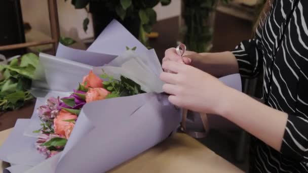 Professionele bloemist bindt een boeket met zijden lint. Mooi boeket voor Internationale Vrouwendag. — Stockvideo