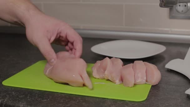Un hombre corta una pechuga de pollo en una tabla de cortar. — Vídeo de stock