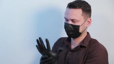 Genç adam ellerine lastik eldiven takıyor..