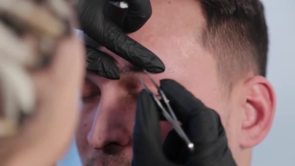 Cejas arranca las cejas a un hombre en un salón de belleza . — Vídeo de stock