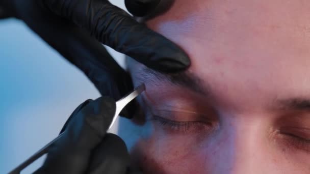 Cejas arranca las cejas a un hombre en un salón de belleza . — Vídeo de stock