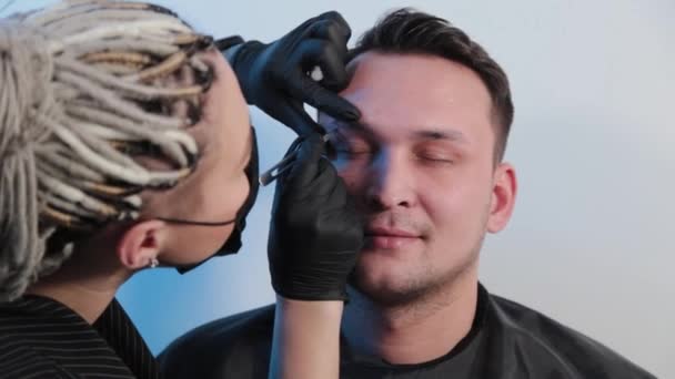 Cejas arranca las cejas a un hombre en un salón de belleza . — Vídeo de stock