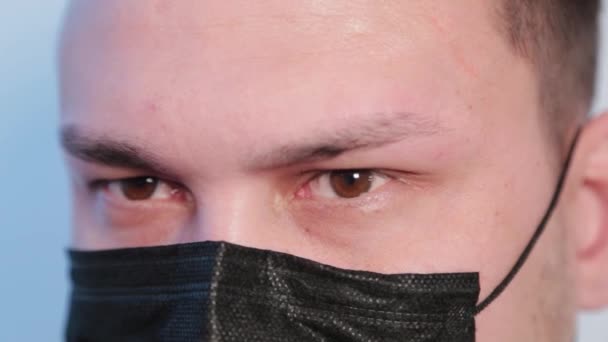 Un joven se pone una máscara protectora en la cara. . — Vídeo de stock