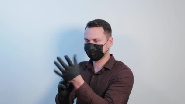 Молодой человек надевает резиновые перчатки на руки . — стоковое видео