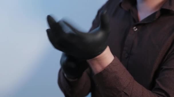 Ο νεαρός βάζει λαστιχένια γάντια στα χέρια του. — Αρχείο Βίντεο
