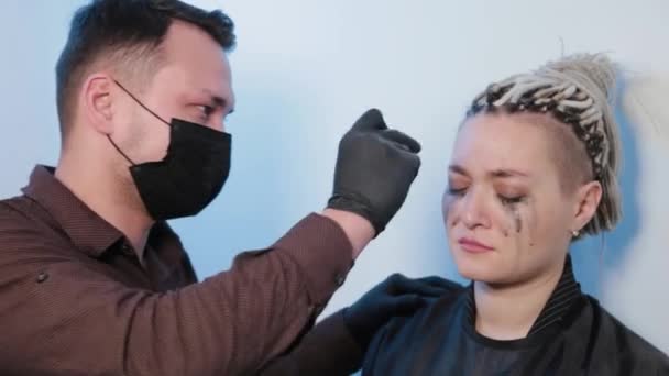 Jovem tira as sobrancelhas com pinças para mulher . — Vídeo de Stock