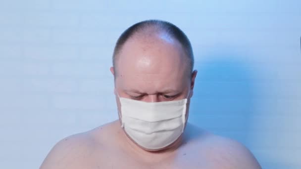 Een man met een medisch masker speelt op de camera. — Stockvideo