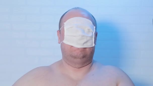 En man i medicinsk mask spelar på kameran. — Stockvideo