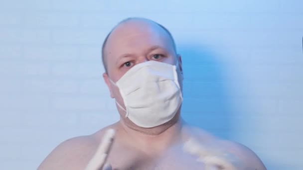 Een man met een medisch masker speelt op de camera. — Stockvideo