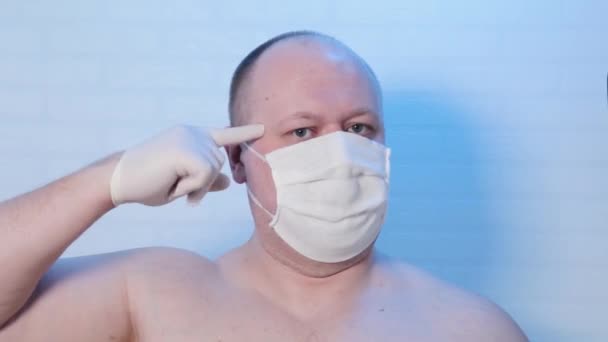 Een man met een medisch masker speelt op de camera. — Stockvideo
