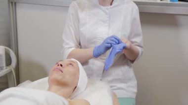 Profesyonel güzellik uzmanı ameliyattan önce lastik eldiven giyer..