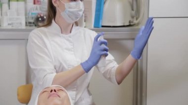 Profesyonel güzellik uzmanı mavi lastik eldivenleri antiseptikle tedavi ediyor.