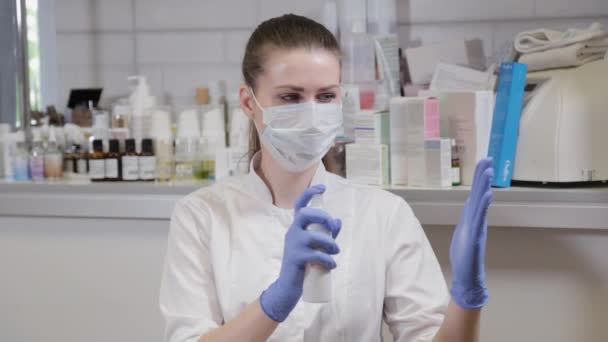 Esthéticienne professionnelle traite des gants en caoutchouc bleu avec un antiseptique — Video