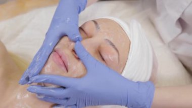 Profesyonel güzellik uzmanı bir kadını yıkar ve yüzüne masaj yapar..