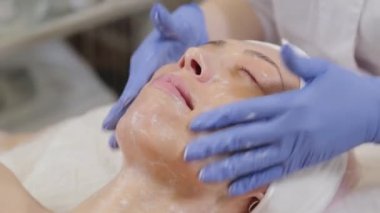 Profesyonel güzellik uzmanı bir kadını yıkar ve yüzüne masaj yapar..