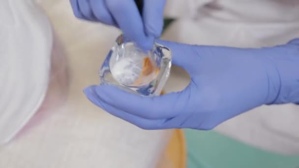 A professional beautician mixes a face mask in a special container. — Stock Video