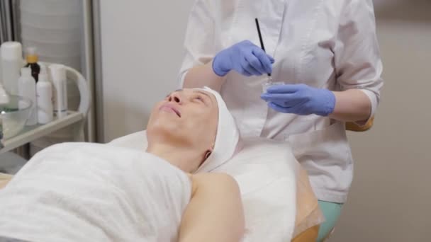 Профессиональный косметолог надевает маску на женщину . — стоковое видео