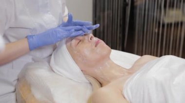 Profesyonel bir güzellik uzmanı bir kadına yüz masajı yapar. Kozmetoloji.