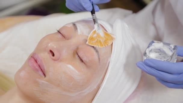 Profesjonalny kosmetyk nakładający maskę na twarz kobiecie. — Wideo stockowe