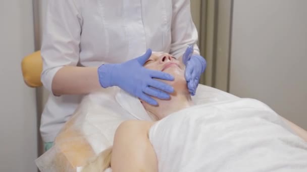 Un'estetista professionista fa massaggi facciali a una donna. Cosmetologia . — Video Stock