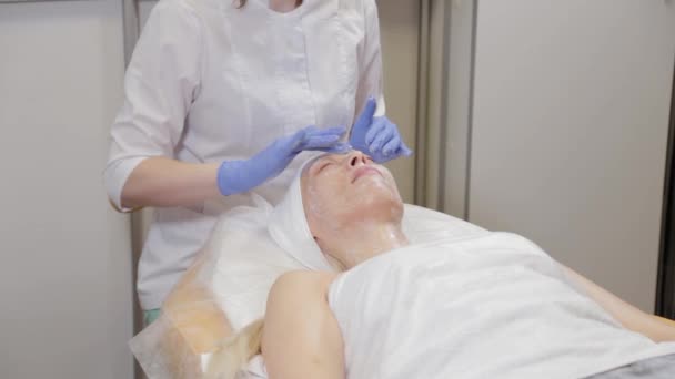 一个专业的美容师给一个女人做面部按摩。化妆品学. — 图库视频影像