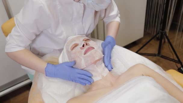 Profesional pone mascarilla facial a cliente mujer. Cosmetología . — Vídeo de stock