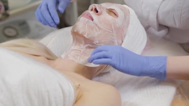 Professional puts face mask to woman client. Cosmetology. — Stock Video