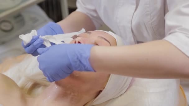 Professioneel zet gezichtsmasker op vrouwelijke cliënt. Cosmetologie. — Stockvideo